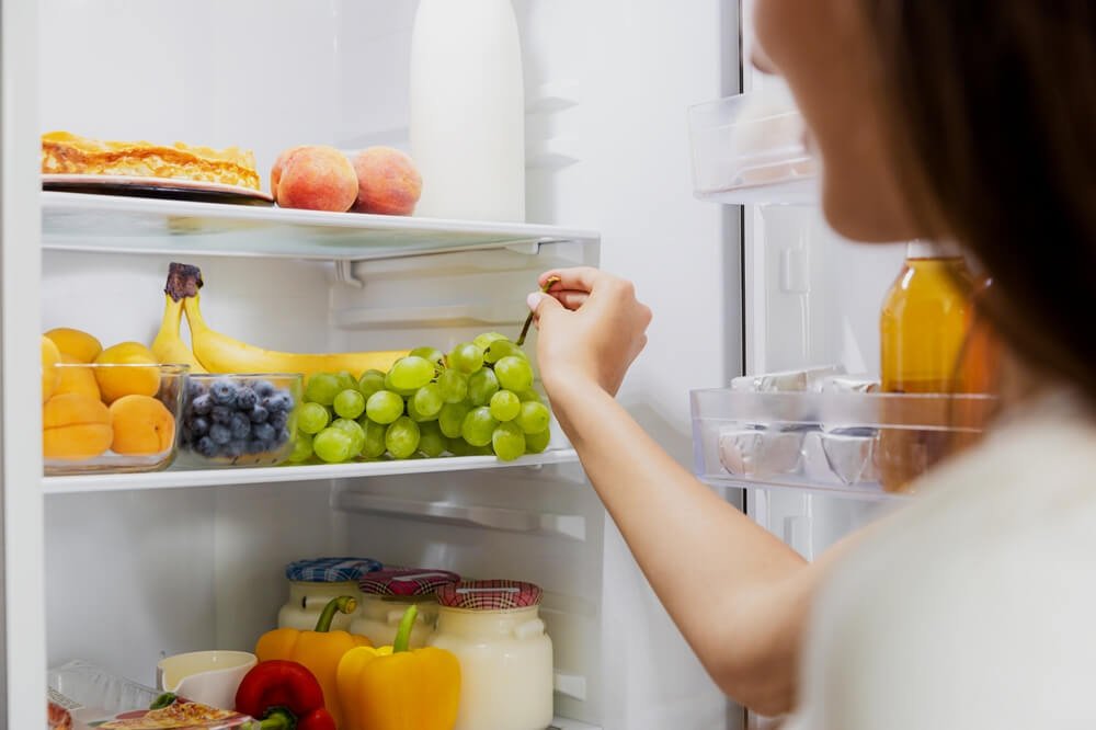 Полки холодильника, на которых аккуратно размещены разнообразные продукты питания: овощи и фрукты в специальных ящиках, молочные продукты в одной зоне, мясо и рыба в другой.